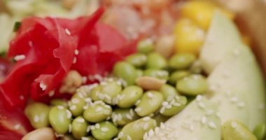 Poke bowl with salmon, rice, avocado, edamame beans, cucumber on a wooden background. Poke bowl, traditional Hawaiian raw fish salad. Organic and clean eating. Fresh fish and vegetables on diet lunch.