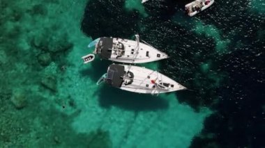 Yachting. Luxury Sail boat. Summer luxury modern boat trip. White yacht. Sailboat. Luxury cruise trip. View from above of white boat on deep blue water. Aerial top down view of rich yacht sailing sea.