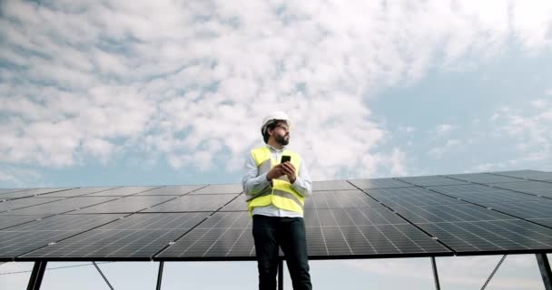 태양열 농장에서 스마트폰으로 통화하는 기술자 발전소의 날에는 각도의 근처를 날에는 — 비디오