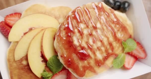 ブルーベリー ミントの葉 イチゴとメープルシロップとアメリカのバターミルクパンケーキ おいしい甘い朝食食品 健康的な朝食を食べる 新鮮さと健康の栄養 — ストック動画
