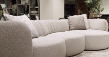 Beyaz, bej mobilyalı ve beyaz mutfak odalı modern Minimalist oturma odası. Köşedeki kanepe, sandalye ve kitaplığı olan lüks modern ev içi. Gayrimenkul özel evi.