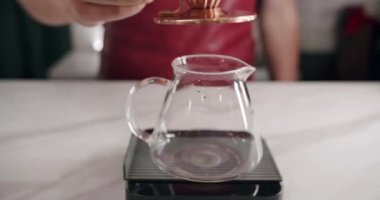 Ekin adam filtre kahve yaparken su dolduruyor. Önlüklü tanınmayan bir erkek barista, modern kafede kahve hazırlarken çaydanlıktan fincana su dolduruyor..