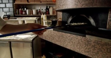 Şef restoran mutfağında pizza hazırlıyor. Büyük hamurlu İtalyan Napoli pizzası. Mutfakta çalış. Pizza ahşap fırına konur. Modern fırın. Pizza.. 