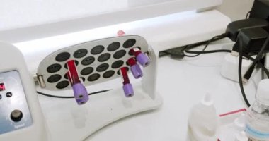 Bir laboratuvar karıştırıcı test tüpünü karıştırmak için kan örneğiyle çevirir. Titretici kanın yerleşmesine ve pıhtılaşmasına izin vermiyor. Laboratuvar ekipmanı konsepti. Vakutainer kanı karıştırıcıda karışıyor.