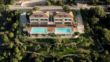 Aerial Upward Shot Of Luxurious Villas with large pool Amidst Green Trees On Mountains. Modern house in a mountain forest. Home exterior with forest. Luxury house in forest.
