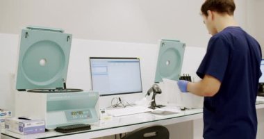 Handheld shot of male medical specialist in uniform preparing samples and using analyzing machine during work in lab of modern hospital. Man working in clinic laboratory.