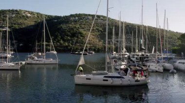 Marine port for yacht. Aerial top view of boats and yachts in marina from above. Yacht parking. Summer sea cruise on ship at green mountains island. White yacht . Sailboat. Luxury cruise trip.