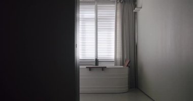 Modern banyonun içinde saydam sürgülü kapı, beyaz ve gri renkli ahşap aksesuarlı minimalist küvet. Modern Minimalist Beyaz Banyo. Beyaz, modern banyo küveti. Lüks Ev.