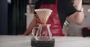 Crop man pouring water while making filter coffee. Crop unrecognizable male barista in apron filling water from kettle into cup while preparing pour over coffee in modern cafe. Barista prepares coffee