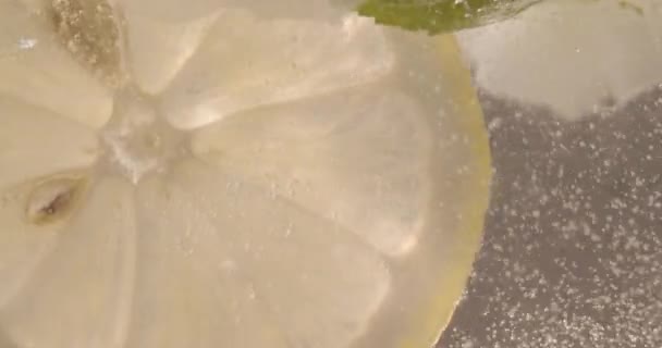 スローモーション水泡でレモンスライスのマクロショット 氷とソフトドリンク ミントとレモン リフレッシュメントが輝くレモンソーダと冷たい夏の飲み物を閉じます — ストック動画