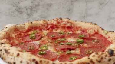 Yakın çekim ve Yavaş çekim acı yeşil biber biberli pizzanın üzerine düşer. Pepperonili hazır. Yemek servisi. Taze biberli pizza. Lezzetli İtalyan pizzası Napoli. 