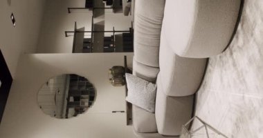 Beyaz mobilyalı modern Minimalist oturma odası. Köşedeki kanepe, sandalye ve kitaplığı olan lüks modern ev içi. Lüks Zarif Oda. Gayrimenkul özel evi. Dikey video.