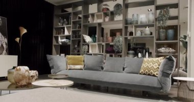 Gri mobilyalı modern Minimalist oturma odası. Köşedeki kanepe, sandalye ve kitaplığı olan lüks modern ev içi. Minimalist İç İşleri. Konforlu Modern Mobilya Tasarımı.