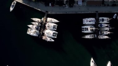 Marine port for yacht. Aerial top view of boats and yachts in marina from above. Yacht parking. Summer sea cruise on ship at green mountains island. White yacht . Sailboat. Luxury cruise trip.