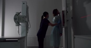 Machine while Female Doctor Adjusts it. Healthy Patient Undergoes Routine Scanning with the Nurses Help.