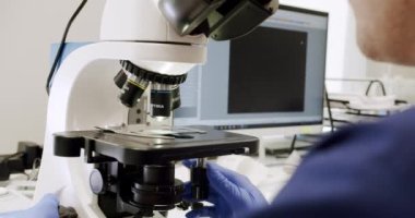 The doctor examines the sperm samples under a microscope. Scientist in sperm laboratory. Analyze sperm cells fertilizing ovum egg under microscope, doctor looking at human fertilization process.
