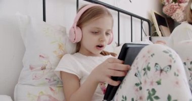 Tatlı çocuklar eğitim için dizüstü bilgisayar kullanıyor, online eğitim, ev eğitimi, çocuklar internetten dil öğreniyor. Çocuklar çevrimiçi oynuyor. Anaokulundan bir çocukla görüntülü konuşma. Dijital tablet ve kulaklık kullanan kız çocukları.