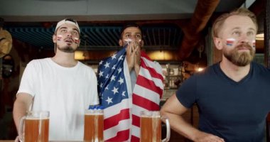 Friends in a Pub. Supporters. Unhappy mixed race supporters are disappointed by the loss of their favorite team. Friends at the bar in a pub having fun. drink beer and watch sports matches.