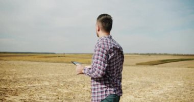 Genç çiftçi tarlada çalışıyor. Kalite kontrol yeşil süpürge çiftliği. yeşil buğday hasadı tarım endüstrisi. Dijital tabletli çiftçi tahıl tarlasını kontrol ediyor..