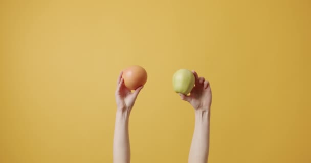Девочки Держат Руках Апельсиновый Зеленый Яблочный Фрукт Изолированном Желтом Фоне — стоковое видео