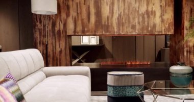 Modern apartman güzel bej kanepe modern oturma odasında lamba, halı, masa. İskandinav iç mimarisi, ahşap duvar, modern gri ve bej kumaş kanepe. Yastıklı tekstil döşeme kanepesi..