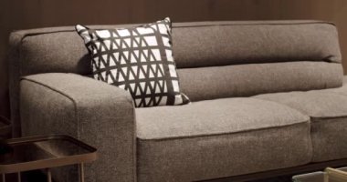 Yastıklı tekstil döşeme kanepesi. Modern apartman güzel bej kanepe modern oturma odasında lamba, halı, masa. Ahşap duvarlı İskandinav iç mimarisi. Modern gri ve bej kumaş kanepe