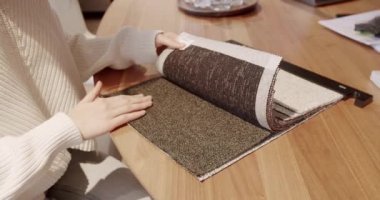 Tekstil galerisindeki renk paletinden kumaş seçen kadın ellerini kapatın. Çok renkli kumaş dokusu arka planı. Kadın mağazadan renk kumaşı seçiyor. Renkli kumaş örnekleri olan tekstil mağazası