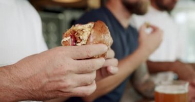 Çeşitli arkadaşlar barda hamburgerin tadını çıkarıyor. Haftasonu barda bira içerken lezzetli hamburgerleri yiyen ve ısıran çok yönlü adamların el kamerası görüntüleri.