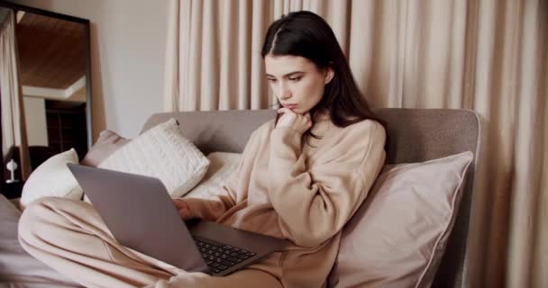 女性は彼女の寝室のノートパソコンで働いています 自宅の概念から仕事 自己隔離 コロナウイルス 若いです美しいです女性使用してノートパソコンアプリ着用Pyjama座っていますで居心地の良いベッドで朝 — ストック動画