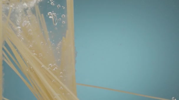 Медленное Движение Падения Сырой Итальянской Пасты Спагетти Воду Голубой Backgorund — стоковое видео