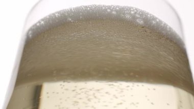 Glass of champagne on white isolated background. Champagne bubbles. Slow motion and super macro shot of tiny air bubbles flowing upwards in elegant glass of champagne on a white background