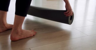 Bir kadın yoga yapmak için bir minder açıyor, sağlıklı yaşam tarzından zevk alıyor spor salonunda egzersiz yapıyor, yoga sınıfında meditasyon yapıyor.