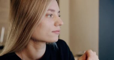 Kafede kahve karıştıran serbest çalışan bir kadın. Kafeteryada uzaktan çalışma sırasında taze kahveyi fincanda karıştıran şık elbiseli genç bir kadının el kamerası görüntüsü.