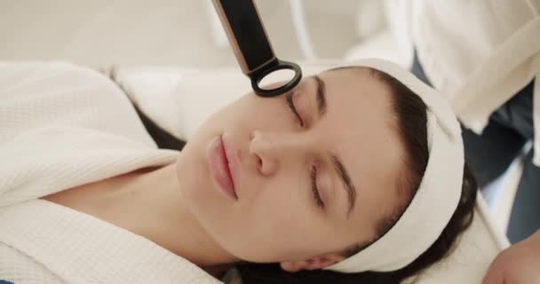 若い女性は 医療センターでレーザー顔の治療を受ける 皮膚の若返り 美容師は レーザー技術を用いた手順画分マイクロニードルメソセラピー若返りを行う — ストック動画