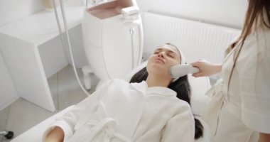 Profesyonel bir kozmetik uzmanı kadın hastalarla güzellik salonunda yüz işlemleri yapar. Profesyonel bir güzellik stüdyosunda LPG deri masajı. Yüz tazeleme prosedürü. Yüz süpürgesi masaj terapisi.