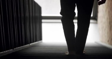 Adam evin ikinci katındaki merdivenlerden iniyor. Çatı katının modern iç kısmı. Büyük sürgülü penceresi ve tuğla duvarı var..