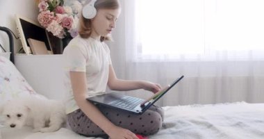 Çocuklar çevrimiçi oynuyor. Anaokulundan bir çocukla görüntülü konuşma. Çocuk dijital tablet ve kulaklık kullanıyor. Tatlı çocuk eğitim için dizüstü bilgisayar kullanıyor, online eğitim, ev eğitimi, çocuk internetten dil öğreniyor..