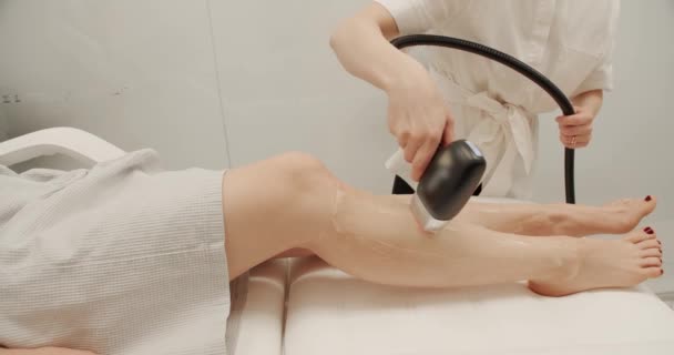 美容師はレーザーを使用して美しい女性の足の毛を削除します 美容室で足の毛のハードウェア除去 レーザー脱毛の美容学 脱毛の手順 レーザーエピレーション — ストック動画