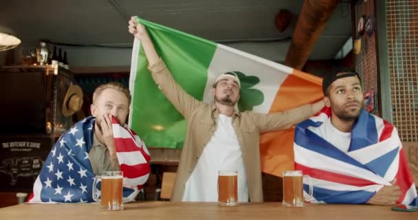 Mężczyźni Flagą Międzynarodowego Kraju Pijący Piwo Oglądający Mecz Sportowy Szczęśliwi — Wideo stockowe