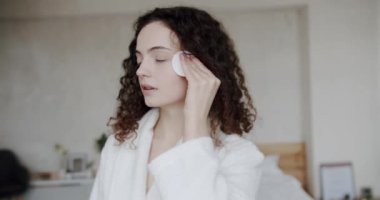 Genç esmer kadın makyajını pamukla temizliyor. Cilt bakımı. Vücut bakımı. Sağlıklı cilt ve temizlik için makyaj malzemelerini çıkarmak için yüz yastıklı bir kadın model. Kendini sev..