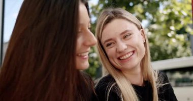 Sokakta kahve içip sohbet eden genç kadınlar. Birlikte güneşli bir hafta sonu günü geçirirken sohbet etmek ve gülmek için el kamerasıyla çekilmiş genç kız arkadaş fotoğrafları.