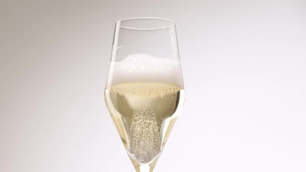 白を背景にしたエレガントなクリスタルガラスにふわふわのシャンパンを注ぐ認識できない人の低い角度 白の隔離された背景にシャンパンのガラス シャンパン泡 — ストック動画