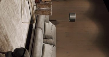 Gri mobilyaları ve tahta duvarları olan modern Minimalist oturma odası. Köşedeki kanepe, sandalye ve kitaplığı olan lüks modern ev içi. Gayrimenkul özel evi. Dikey video.