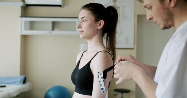 Fysioterapeut Fäster Kinesiologitejp Kvinnans Skuldra Handhållen Bild Glad Man Fästa — Stockvideo