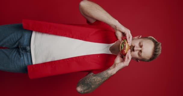 Vídeo Vertical Unshaven Homem Caucasiano Come Hambúrguer Carne Com Prazer — Vídeo de Stock