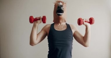 At maskeli komik bir adam evde beyaz arka planda el eğitimi için ağırlık egzersizi yapıyor. Evde komik bir spor salonu var. Komik Sağlık ve Spor Konsepti.