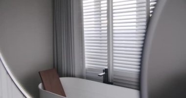 Lüks Banyo İçi, banyo aksesuarları, ayna ve duş başlığı, modern iç mekanda yuvarlak ayna, banyo küveti modern tasarımı olan minimalist iç mimari. Lüks, rahat, beyaz bir daire..