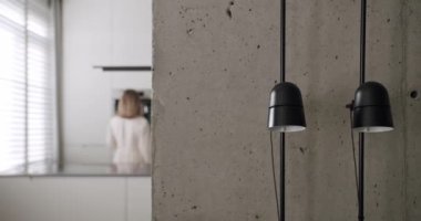 Modern bir mutfak odasında, minimalist bir dairede, beyaz bir evde, beton ve konforlu donanımlı gri renkli bir evde bir kadın kahve yapıyor. modern tasarım ve dekorasyona sahip ev aletleri.