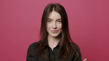 Kutlama, parti, kazanma kavramı. Güzel bir kadın ağır çekimde konfeti üflüyor ve pembe arka planda gülümsüyor. Sevgililer Günü kutlaması. Romantik bir duygu. Neşeli flörtleşme.