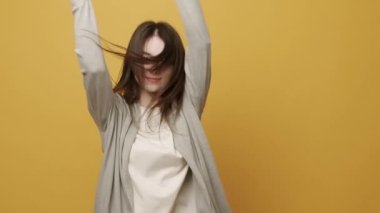 Neşeli Kadın Portresi ellerini oynatmak için ritmik bir şekilde müzik eşliğinde gülümsüyor. Sarı Arkaplanda Zıpla Yavaş Hareket. Dans ediyor, eğleniyor, jestler yapıyor..